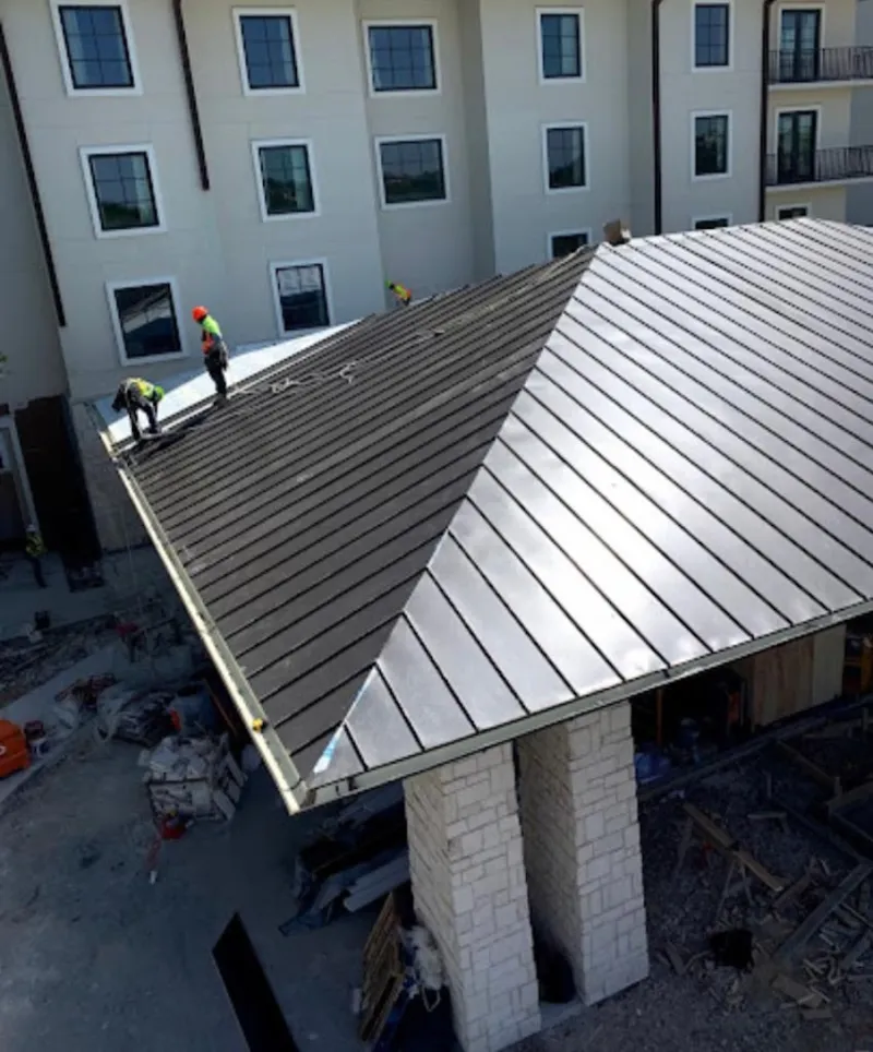 Crew installing standing seam metal roof panels on a commercial project in Hudson